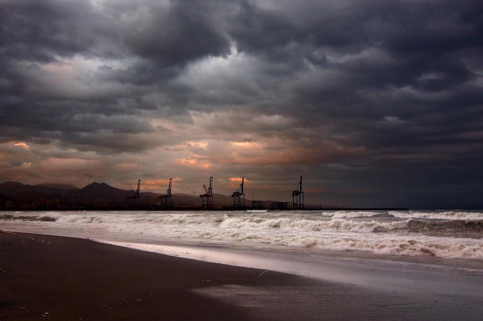 Free Image of Stormy sea with industrial cranes on the horizon. 
