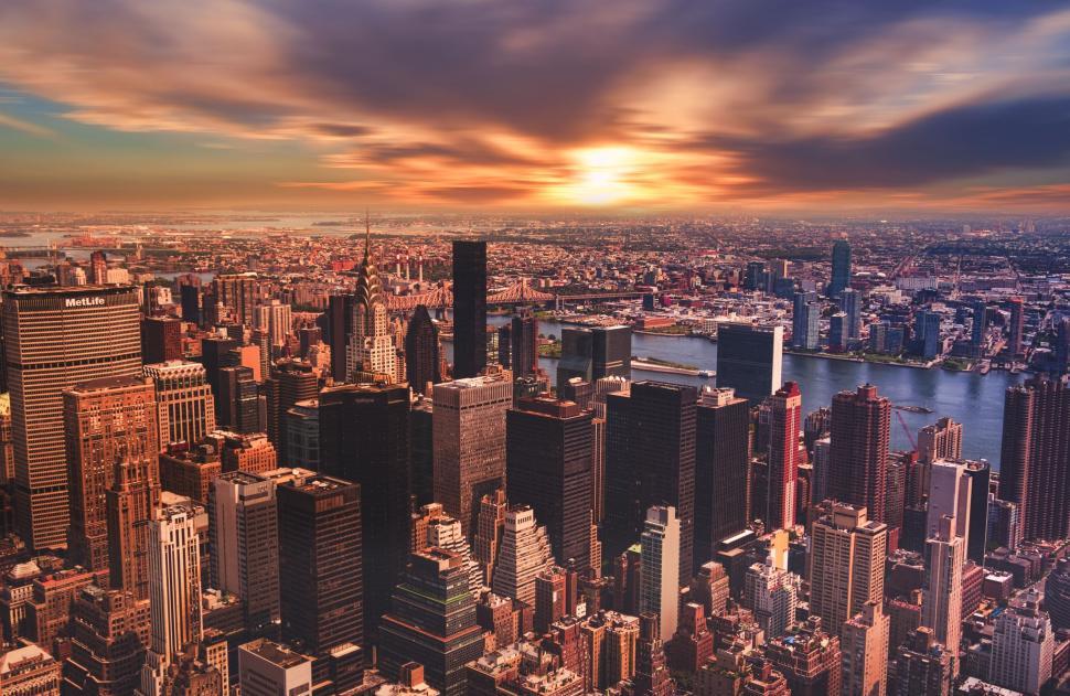 Free Image of Colorful sunset cityscape with high-rise buildings and river 