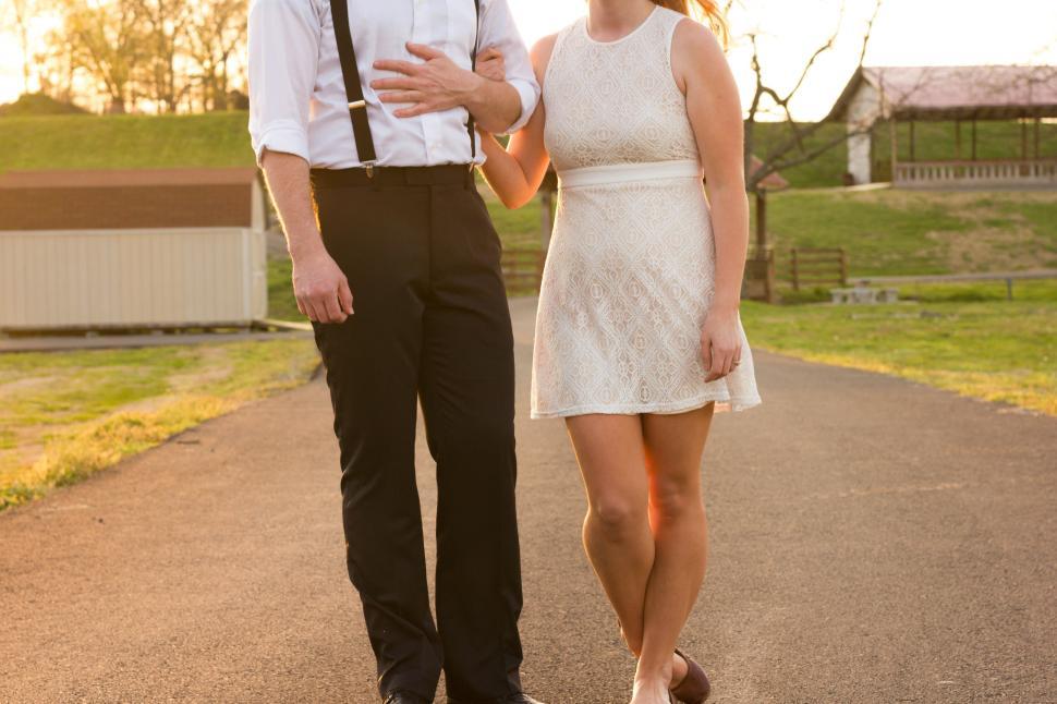 Free Image of Couple walking together on a paved path in warm sunlight 