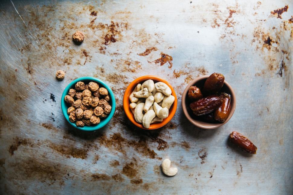 Free Image of Three small bowls with nuts and dates on metal tray. 