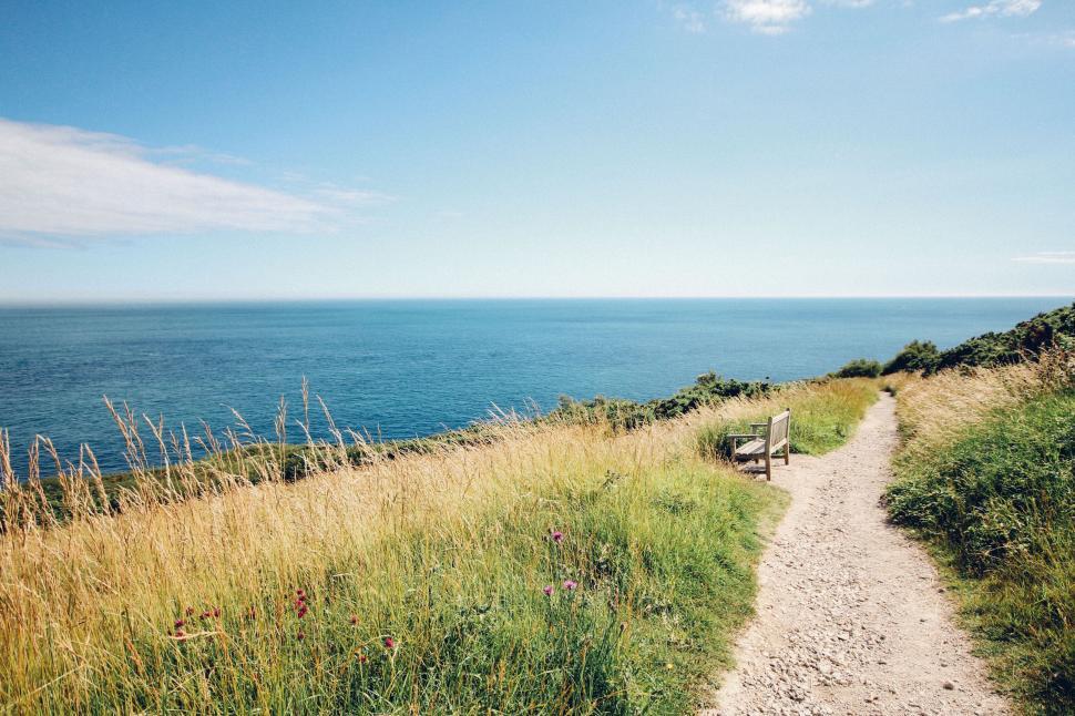 Free Image of Empty bench on coastal path overlooking the ocean view 