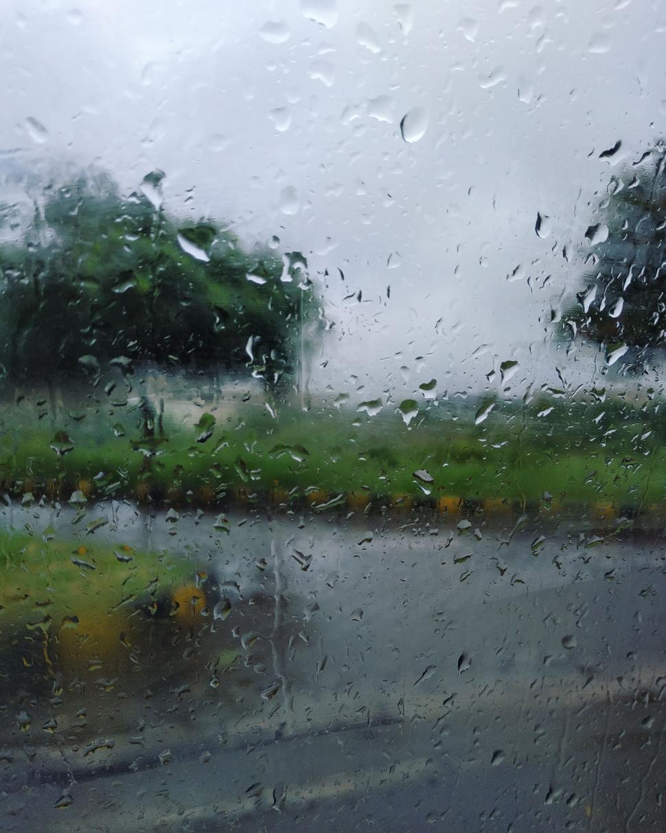 Free Image of Raindrops on a glass window with blurred outdoor view. 