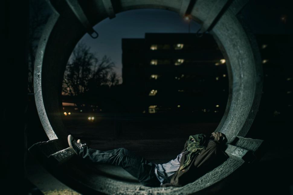 Free Image of Person laying inside a large concrete pipe at night. 