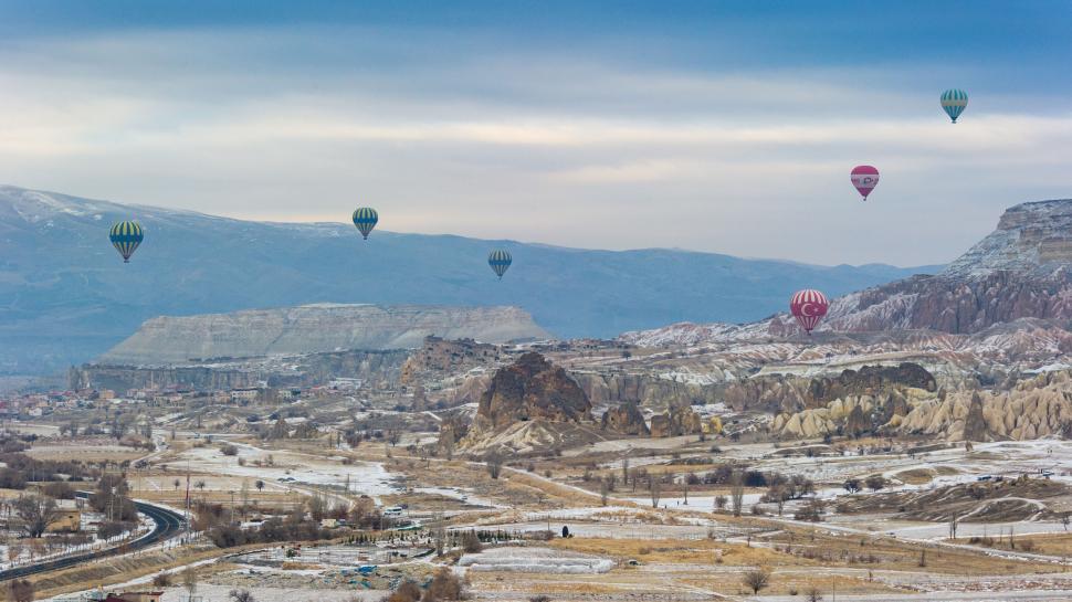 Free Image of Hot air balloons float over a scenic, snowy landscape. 