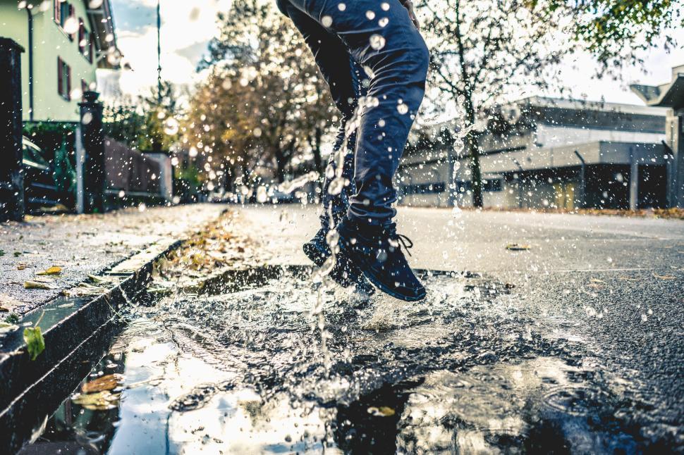 Free Image of Person jumping into a puddle splashing water everywhere 