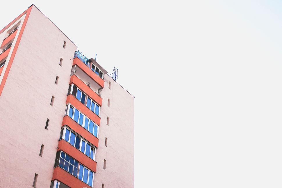 Free Image of Tall light-colored apartment building against bright sky 