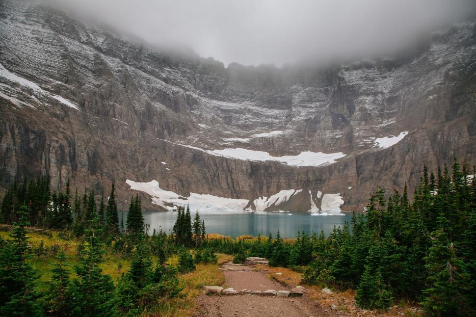 Free Image of Foggy mountain lake surrounded by towering cliffs and trees. 