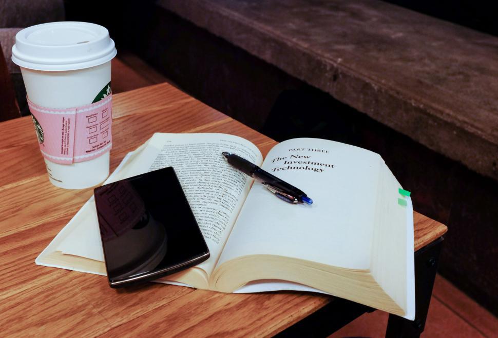 Free Image of Open book with coffee cup, pen, and smartphone on table 