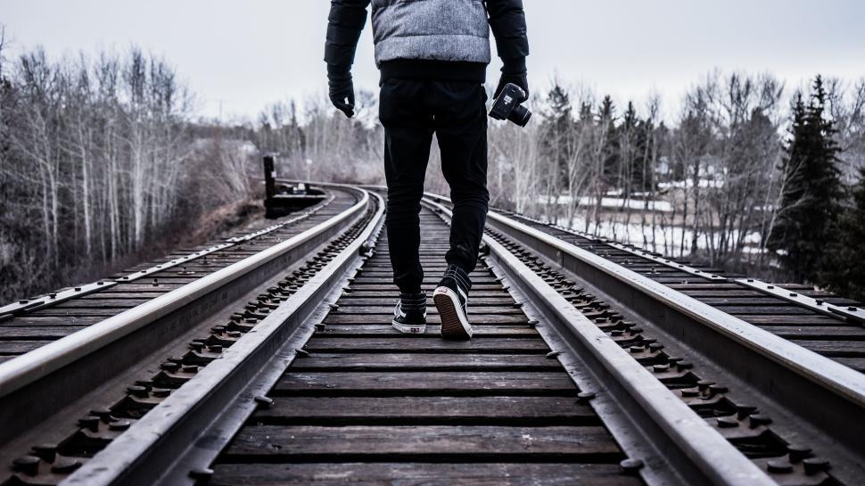 Free Image of Person walking on railway tracks in a winter landscape. 