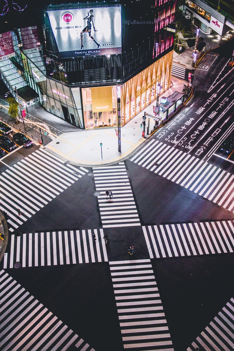 Free Image of Empty Tokyo street crossing at night with illuminated ads 