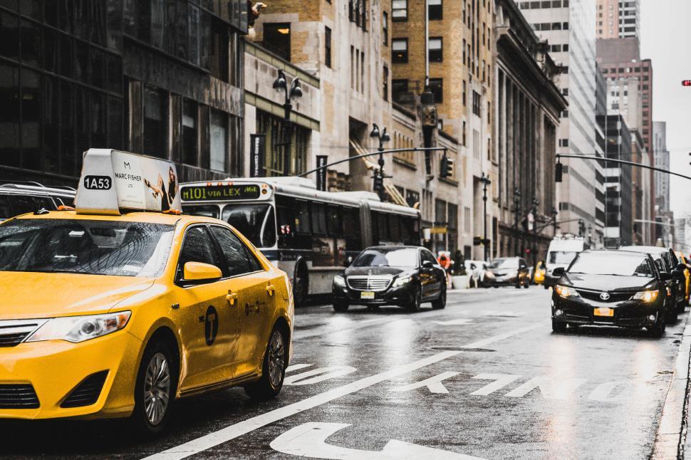 Free Image of Yellow taxi on a rainy day in a bustling city street 