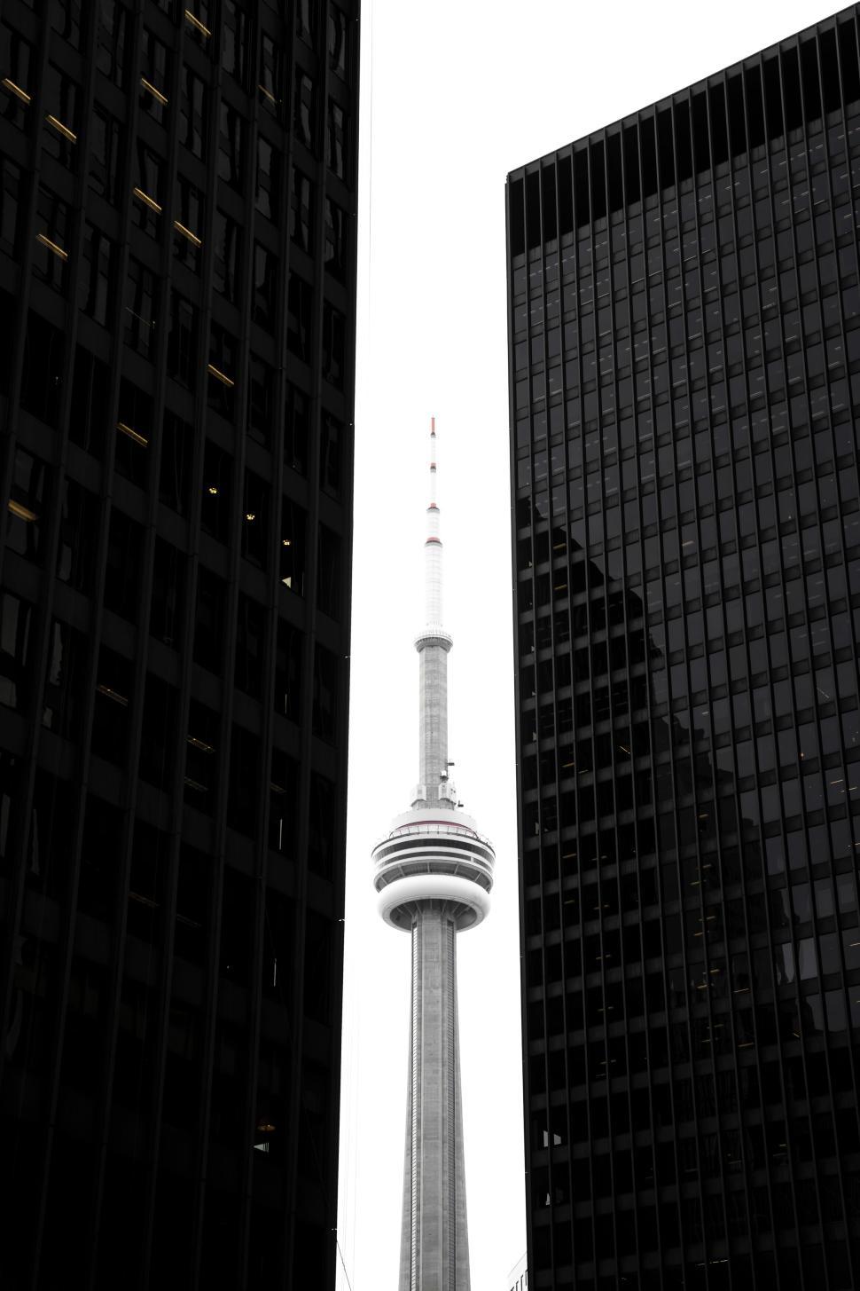 Free Image of Tall iconic tower framed by two dark high-rise buildings. 