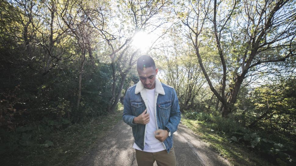 Free Image of Young man in denim jacket on a sunny forest path. 