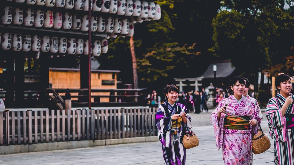 Free Image of Three women in kimonos at a temple with lanterns above. 