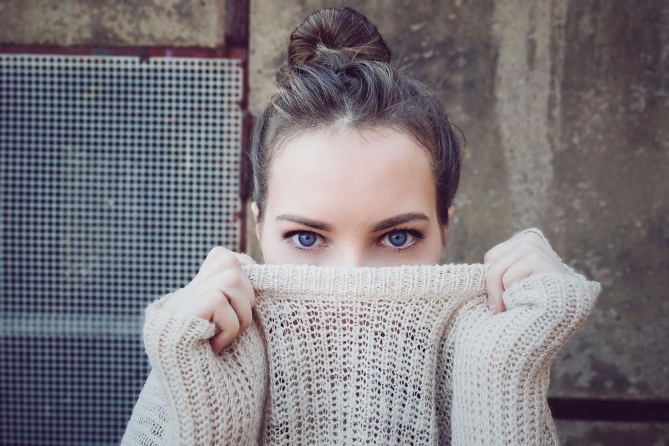 Free Image of Person in sweater with bun, abstract background wall. 