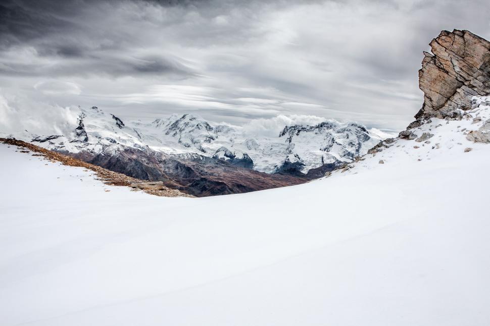 Free Image of Snowy mountains with rocky peak under cloudy sky. 