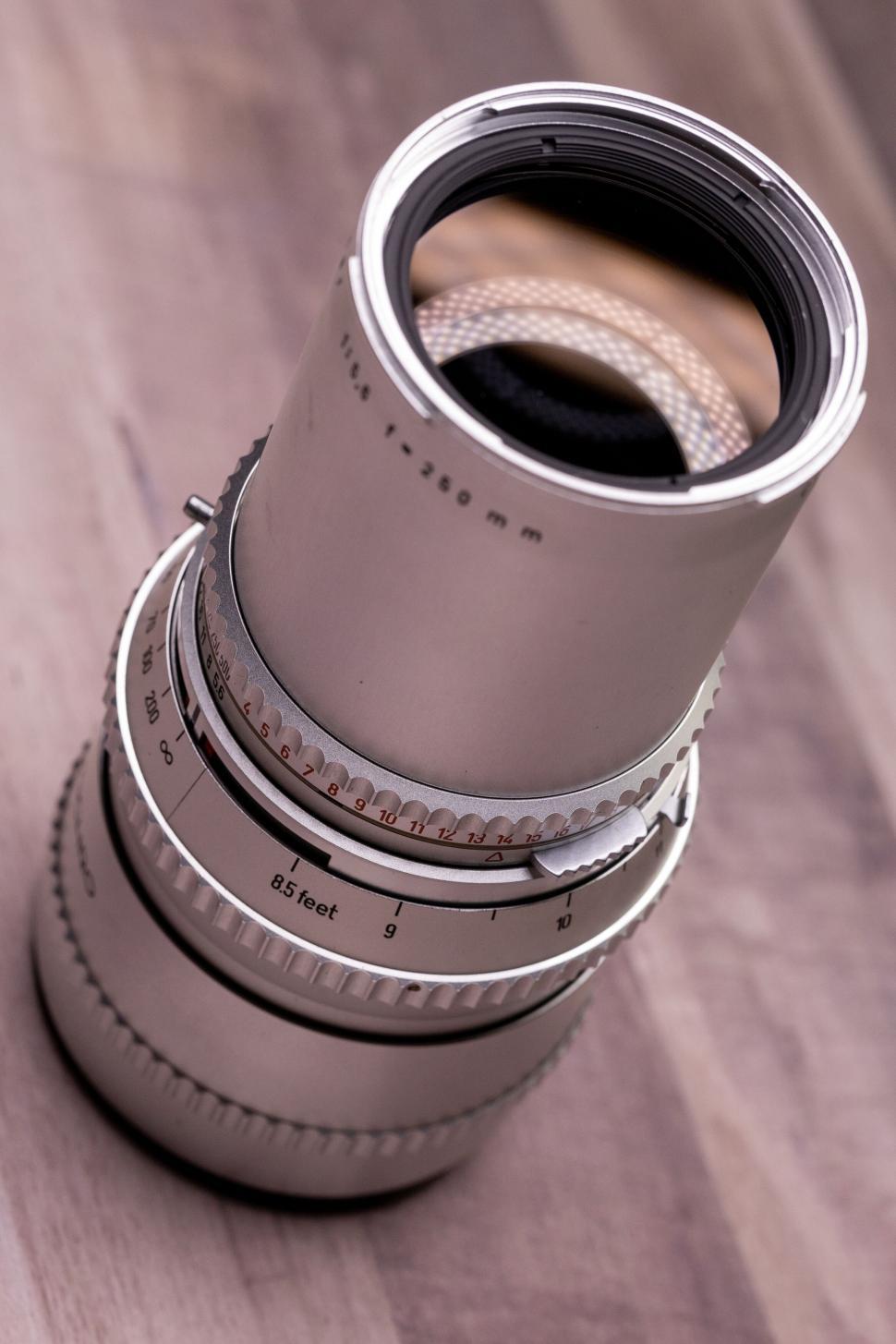 Free Image of Close-up of a white telephoto camera lens on wood. 