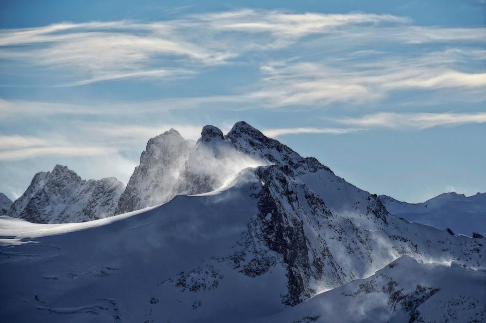 Free Image of Snowy mountain peaks with dramatic sky in background 