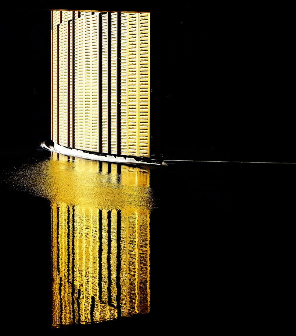 Free Image of Golden vertical bars casting reflection on dark water 