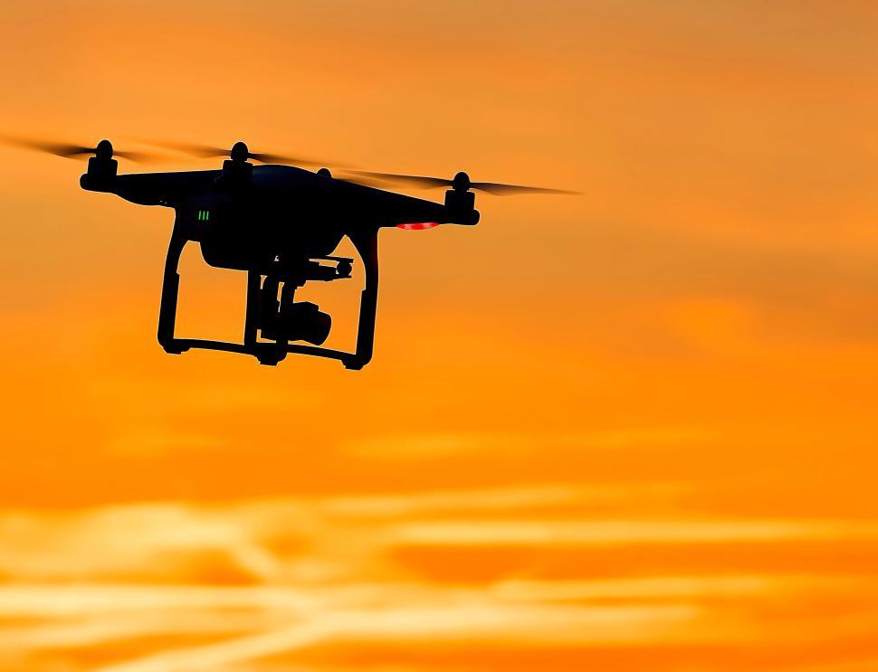 Free Image of Silhouette drone flying in the sky during golden sunset. 