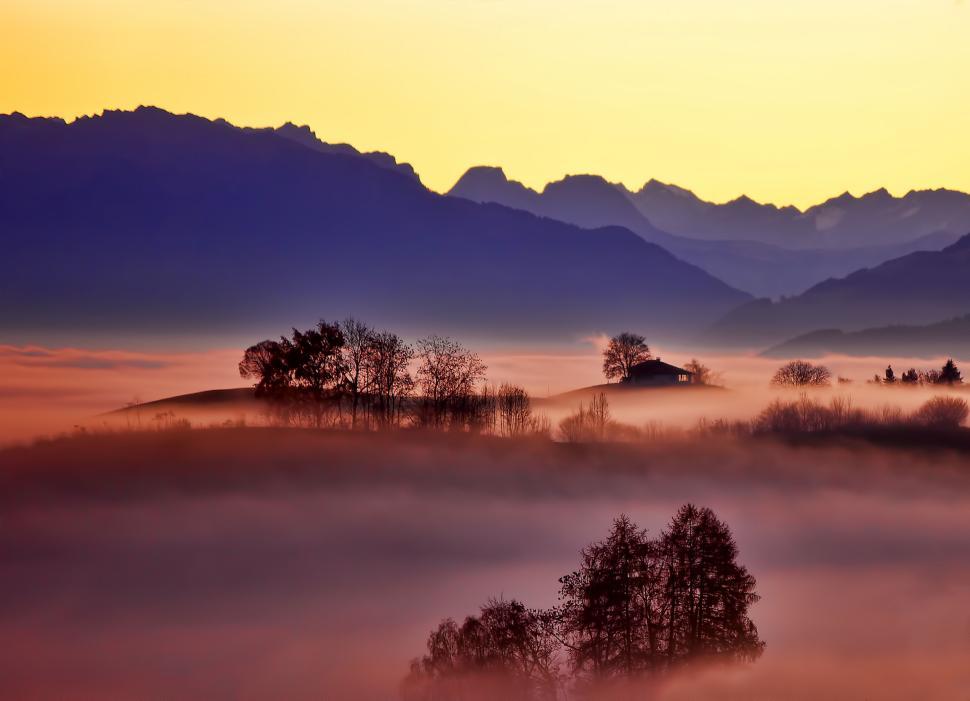 Free Image of Misty landscape with silhouettes of trees and hills 
