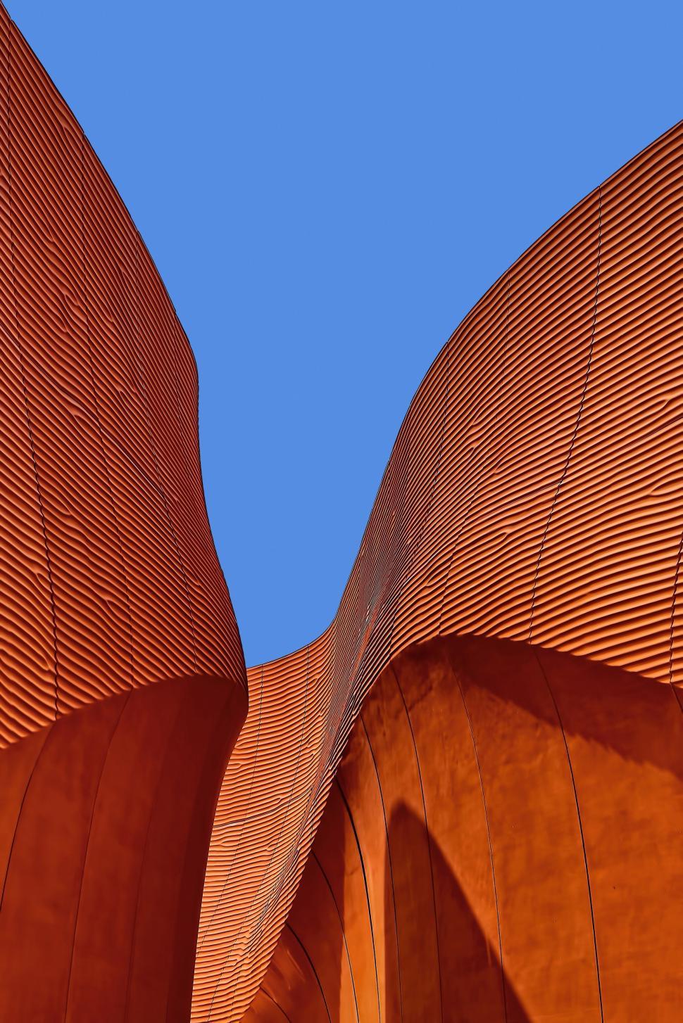 Free Image of Abstract rust-colored modern building against blue sky. 