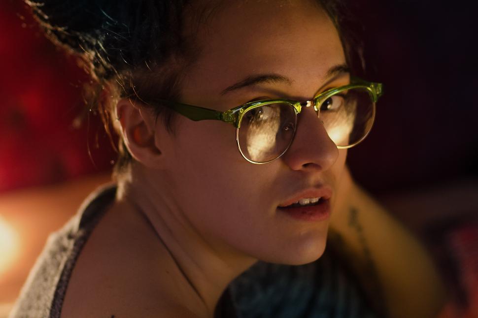 Free Image of Young woman wearing glasses looking curiously upward 