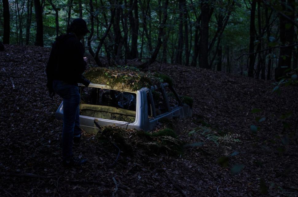 Free Image of Person examining an abandoned old car in the forest 