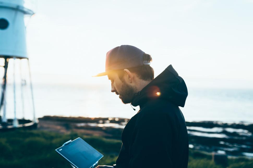 Free Image of Person using laptop near the ocean and lighthouse 