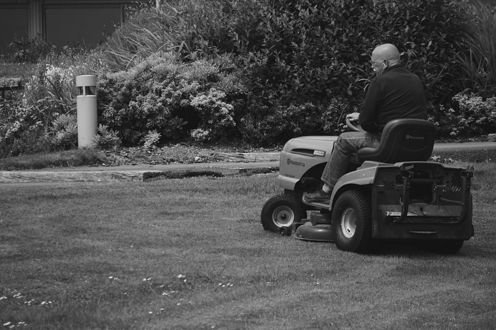 Free Image of Man mowing the lawn with a ride-on mower, black and white. 