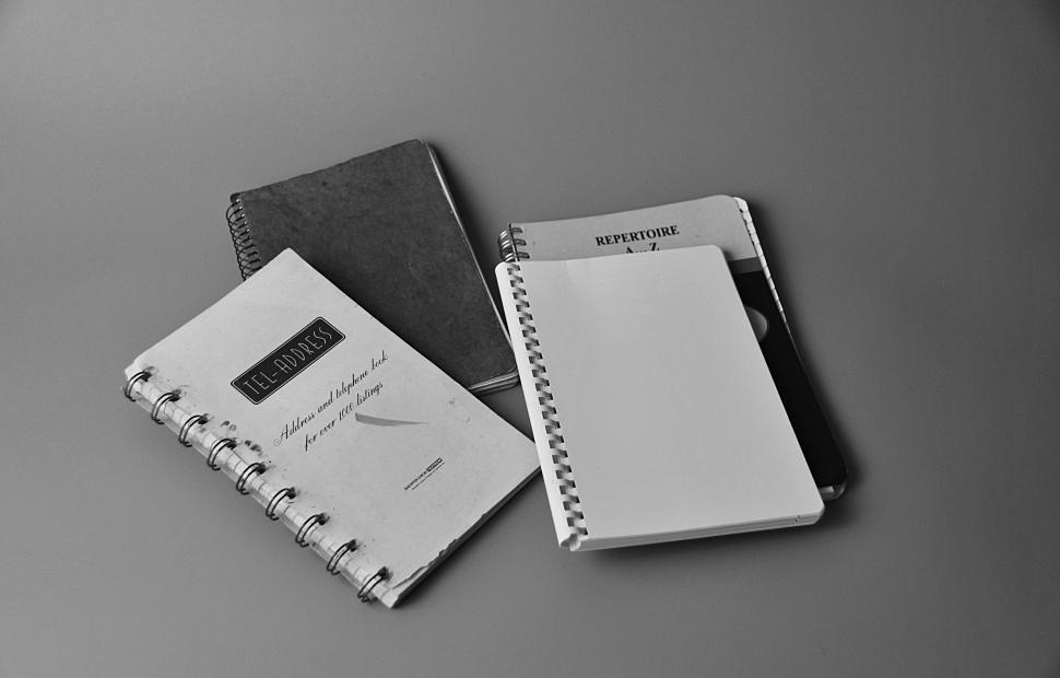Free Image of Collection of notebooks and papers laid out in black and white. 