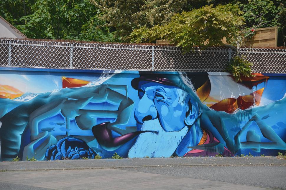 Free Image of Colorful graffiti mural of an old man with a pipe on wall 
