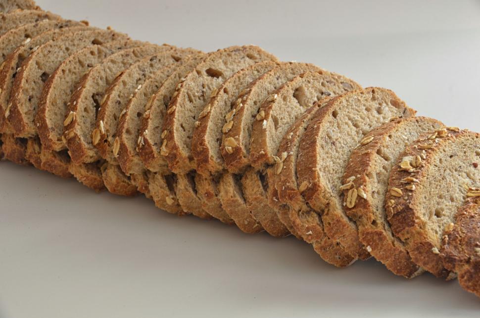 Free Image of A loaf of sliced bread aligned in a neat row. 