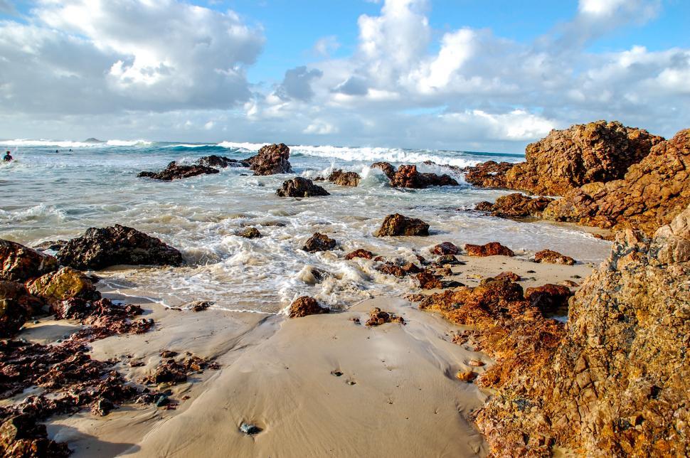 Free Image of Rocky coastal beach scene with waves and cloudy sky. 
