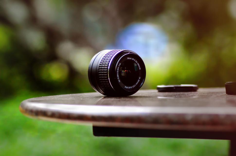 Free Image of Camera lens on outdoor table with blurred background. 