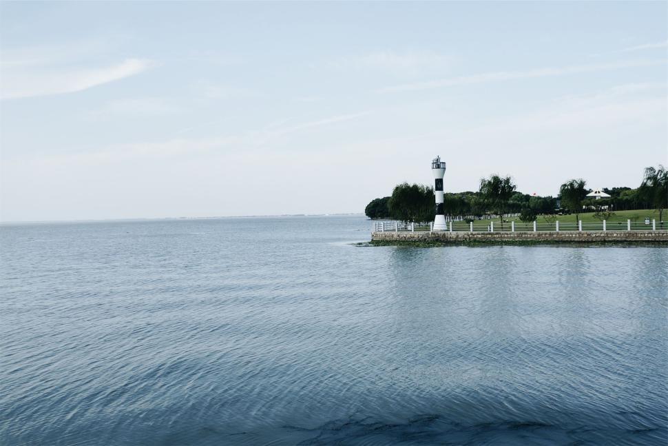 Free Image of Scenic lighthouse with calm blue water in the background 