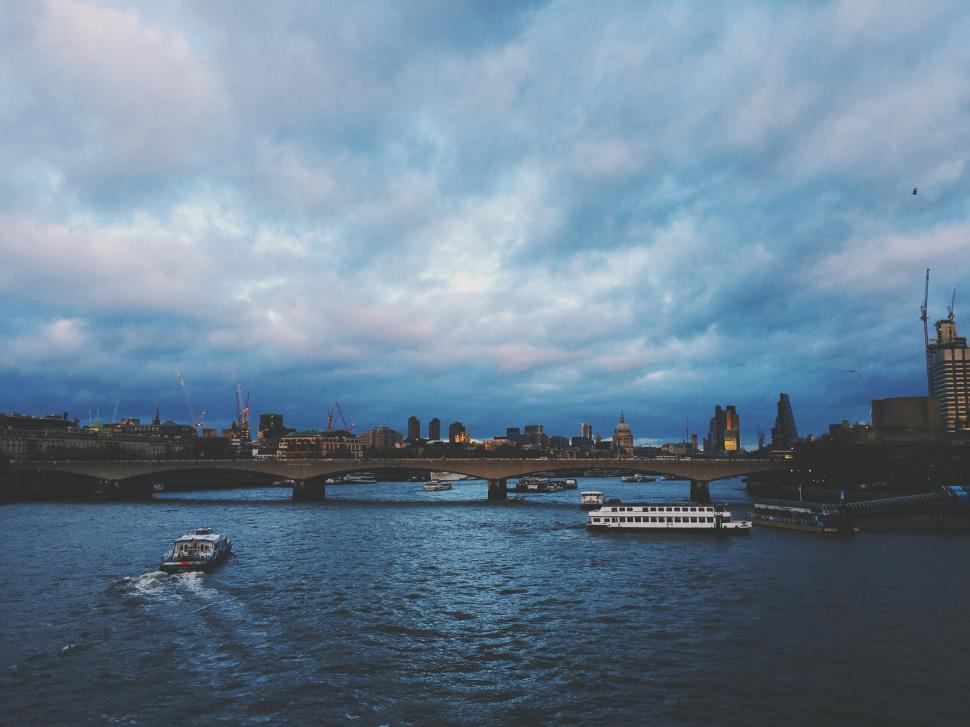 Free Image of Boats cruising on river under city bridge at sunset. 