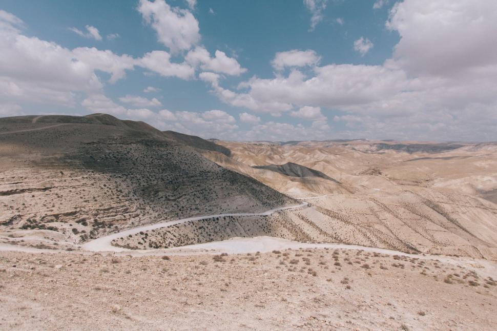 Free Image of Arid mountains with winding road under a blue sky. 