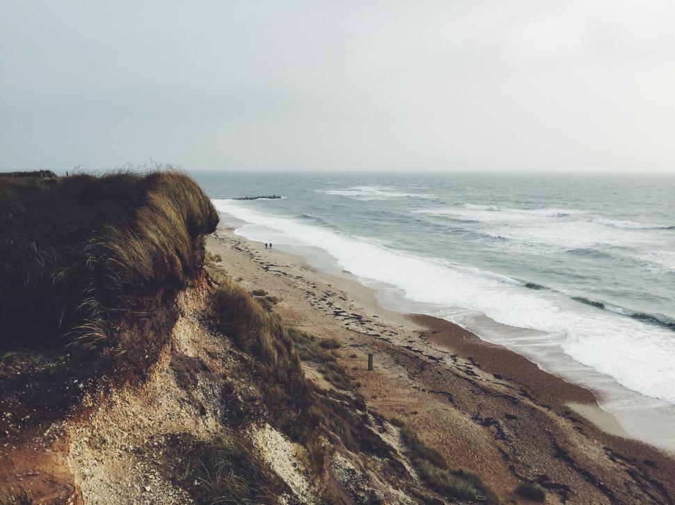 Free Image of Eroding coastline with grass atop cliffs by the sea. 