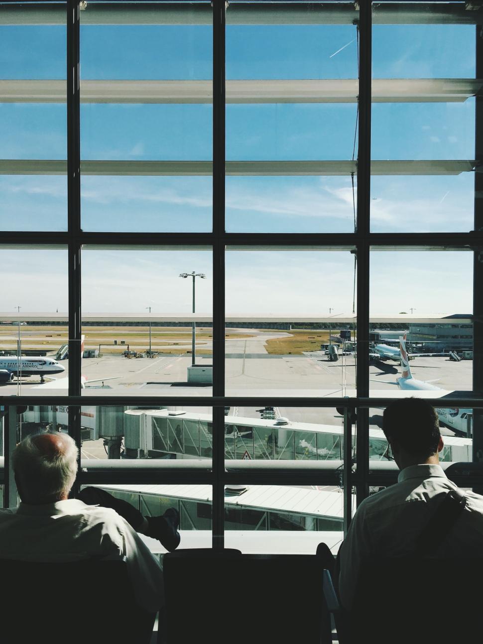 Free Image of Two men waiting at airport terminal by large windows 