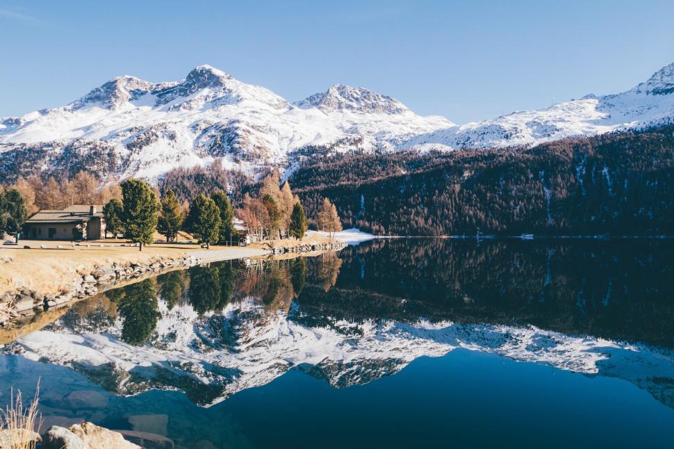 Free Image of Serene lake reflecting snow-capped mountains and trees. 