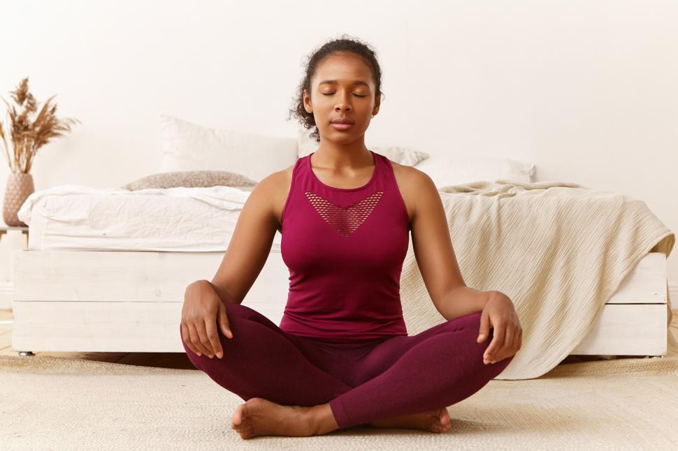 Free Image of Meditation, peace, balance, zen and harmony concept. Portrait of healthy fit young African woman with eyes closed sitting on floor after yoga practice, meditating, doing breathing exercises 