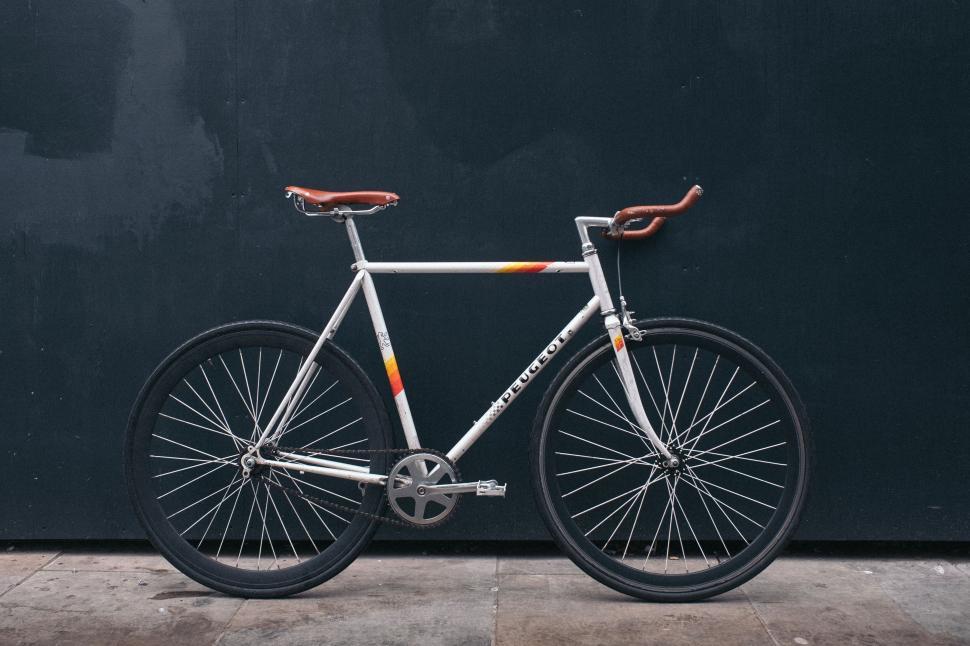 Free Image of Vintage white bicycle against a dark wall background 