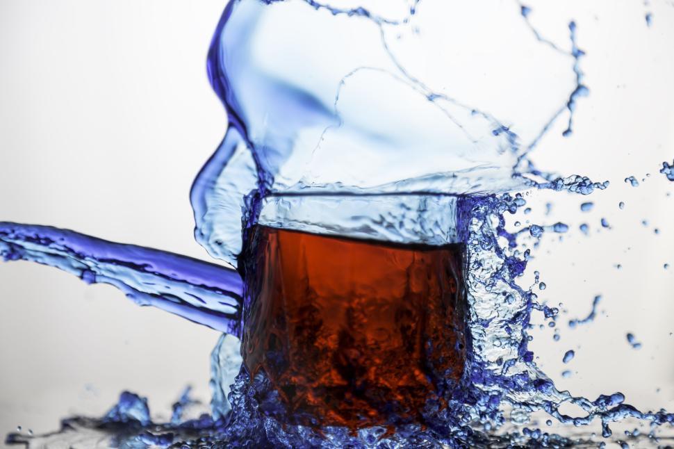 Free Image of Red liquid splash in glass with surrounding blue water. 