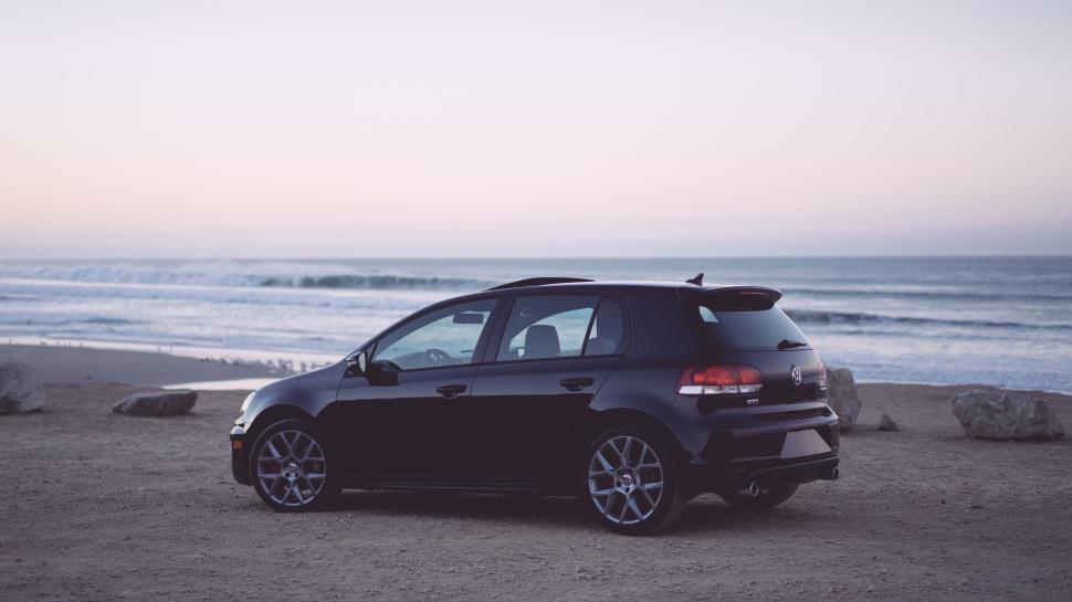 Free Image of Black hatchback car parked near the beach at sunrise. 