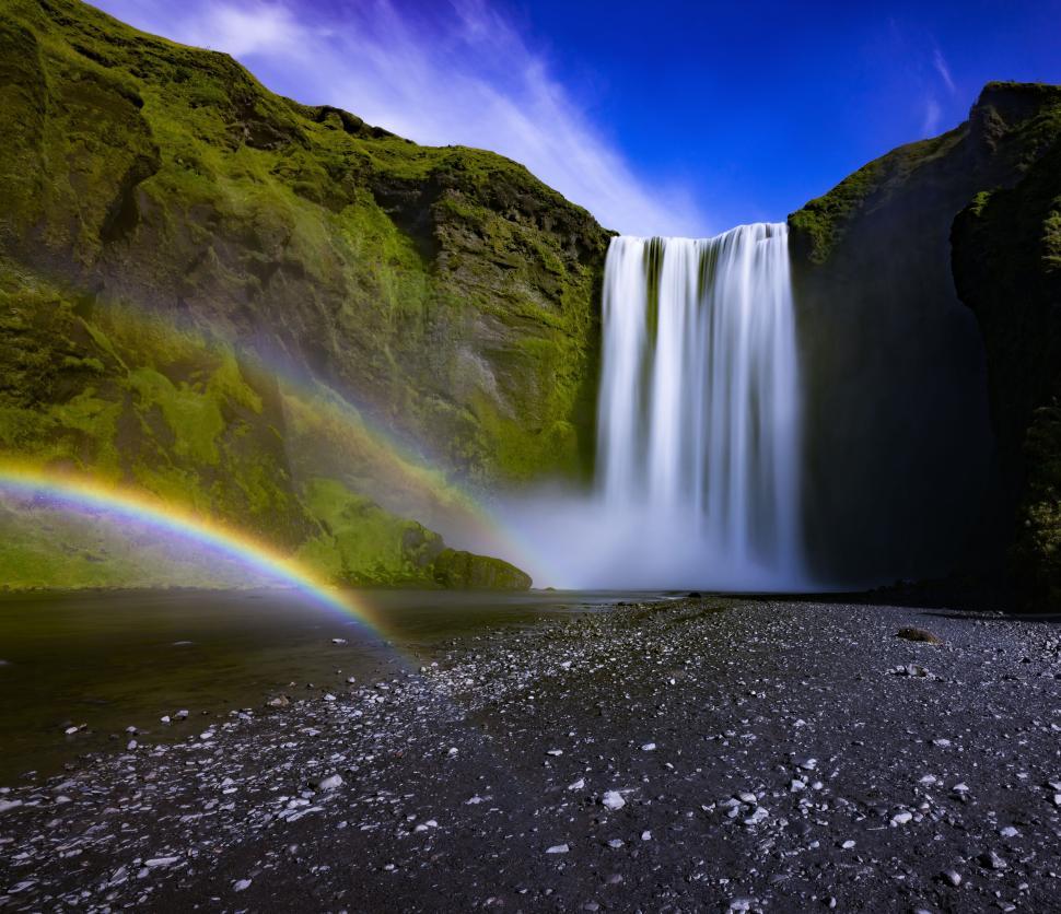 Free Image of Majestic waterfall with double rainbow on sunny day 