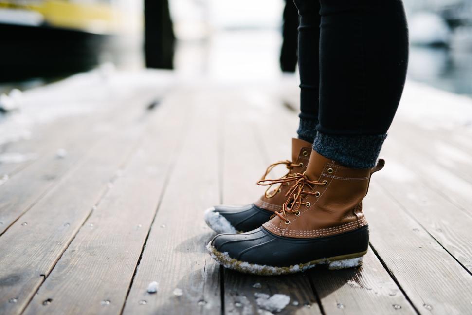 Free Image of Person wearing stylish winter boots standing on wooden deck 