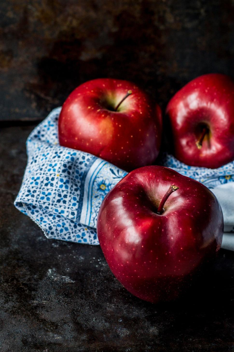 Free Image of Three red apples on a patterned cloth surface setup 