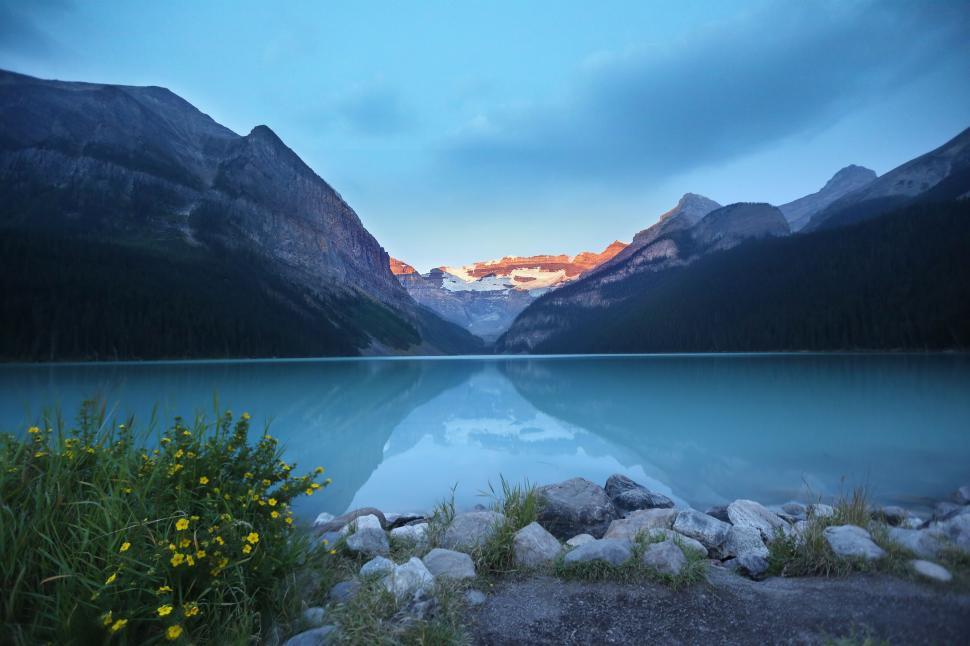 Free Image of Sunrise over serene lake surrounded by high mountains 