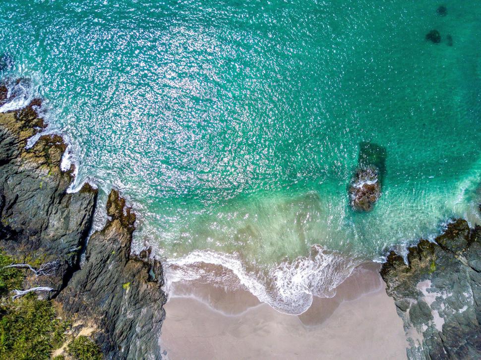 Free Image of Rocky coastline with turquoise ocean water and beach. 